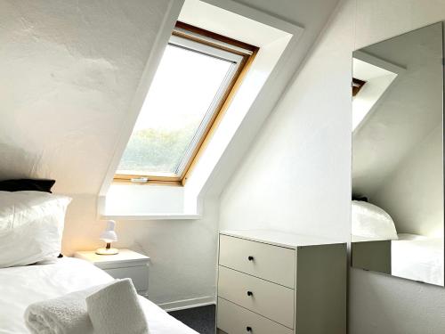 a attic bedroom with a window and a bed and a mirror at Spacious Apartment for 5 in Odense