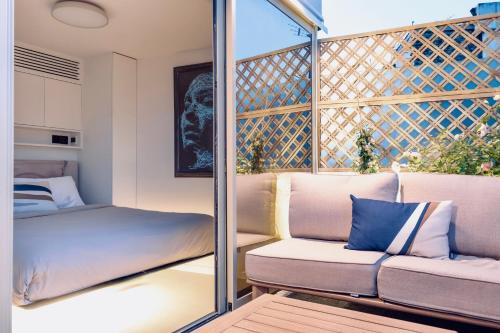 un petit balcon avec un canapé et un lit dans l'établissement Les Terrasses de l Arc, à Paris