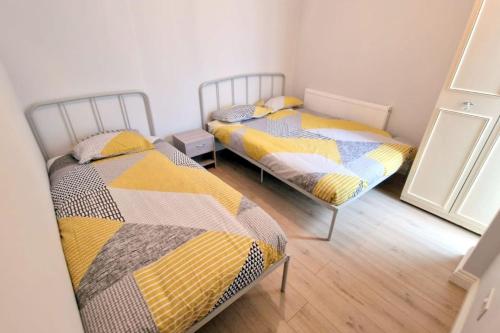 two twin beds in a room with a mirror at 2-bedroom flat in Central Sutton in Sutton