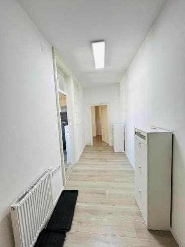 a hallway with white walls and wooden floors and a white refrigerator at Leoben Top 6 in Leitendorf