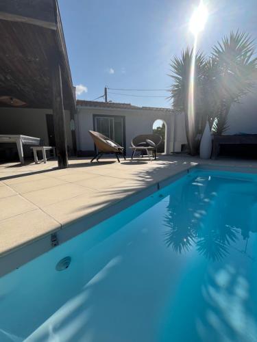 une piscine avec deux chaises à côté d'une maison dans l'établissement Gîte Villa la Garenne Ctre ville St Jean de Monts, à Saint-Jean-de-Monts