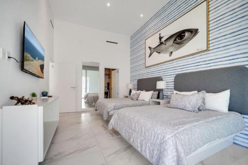 a bedroom with two beds and a fish on the wall at Medano Beach Pvt Jacuzzi Pool Marina Stylish in Cabo San Lucas