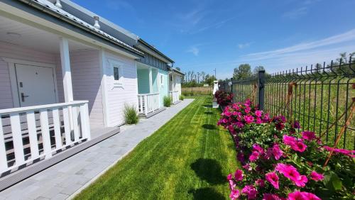 a yard with pink flowers next to a house at Domki letniskowe Pastelowe Ustronie in Ustronie Morskie