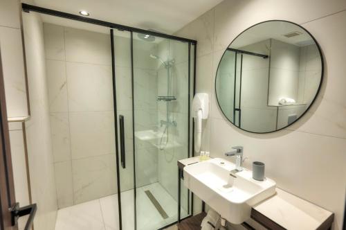 a bathroom with a shower and a sink and a mirror at ASTE hotel in St Julian's