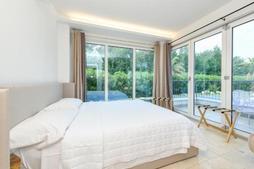 a bedroom with a white bed and a large window at Lastmile apt with terrace&pool near lake&sirmione in Desenzano del Garda