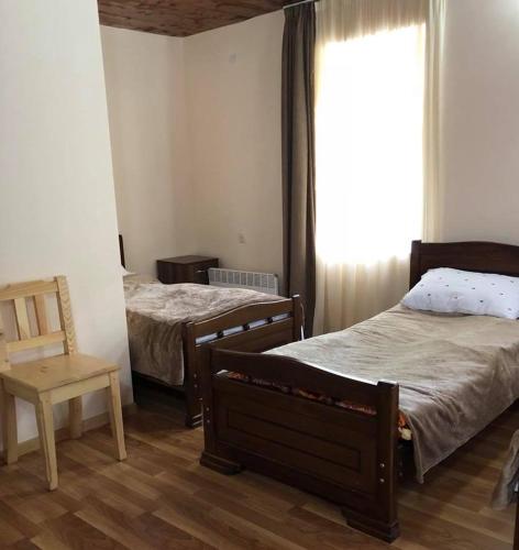 a bedroom with two beds and a chair and a window at guest house dede in Itʼkhvisi