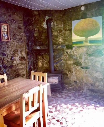 a stone room with a wooden table and a fireplace at guest house dede in Itʼkhvisi