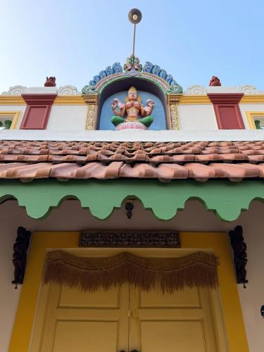 a building with a statue on top of a door at Marutham Village Resort in Mahabalipuram