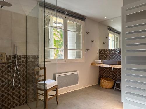 La salle de bains est pourvue d'une douche, d'une chaise et d'une fenêtre. dans l'établissement Maison de village avec piscine, à Saint-Étienne-de-Lolm