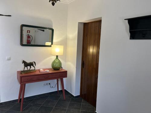 a room with a table with a lamp and a mirror at Casa dos Avós in Campinho