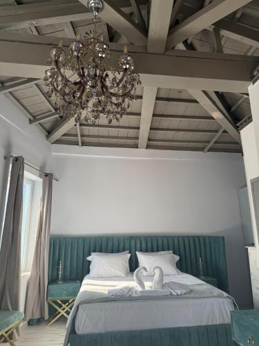 a bedroom with a large bed with a chandelier at Gorgeous restored house at Platanos square in Lésvos