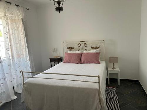 una camera da letto con un letto bianco e cuscini rosa di Casa dos Avós a Campinho