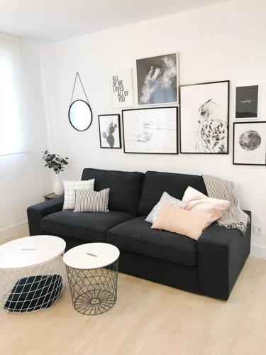 a living room with a black couch and pictures on the wall at Suite Estébanes in Zaragoza