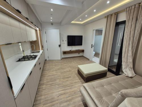 eine Küche und ein Wohnzimmer mit Sofa und Fernseher in der Unterkunft MBM appart in Monastir