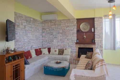 Una sala de estar con un sofá y una pared de piedra. en Sunrise Sanctuary, en Mandoukáta