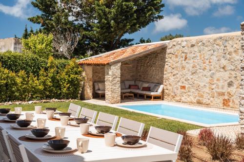 a table with chairs next to a swimming pool at Sea'Ya Thoughtful Stays - Villa Juso in Aldeia de Juso