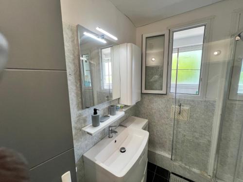 une salle de bain blanche avec un lavabo et un miroir dans l'établissement Magnifique Appartement Montpelliérain, à Montpellier