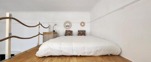 - une chambre blanche avec un lit blanc et du parquet dans l'établissement Studio Xana vue Adour, à Bayonne