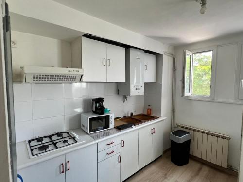 une cuisine blanche avec des armoires blanches et un micro-ondes dans l'établissement Magnifique Appartement Montpelliérain, à Montpellier
