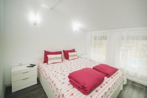 GoranovtsiにあるВила с басейн и джакузиの白いベッドルーム(赤い枕のベッド付)