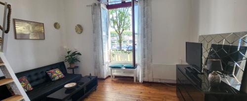 - un salon avec un canapé noir et une fenêtre dans l'établissement Studio Xana vue Adour, à Bayonne