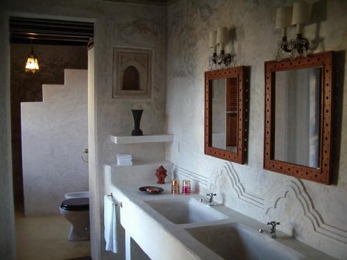 a bathroom with a sink and a mirror and a toilet at LAMU HOUSE in Lamu