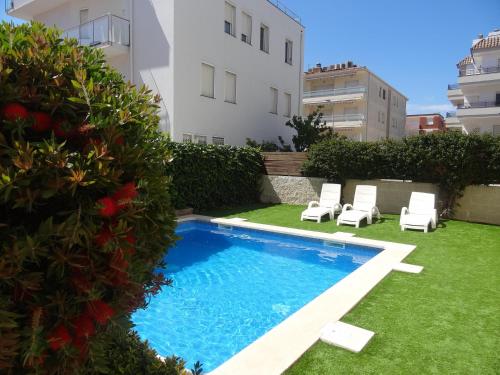 a swimming pool with two lawn chairs and a building at Apartamentos Las Brisas 3-2 in Torroella de Montgrí
