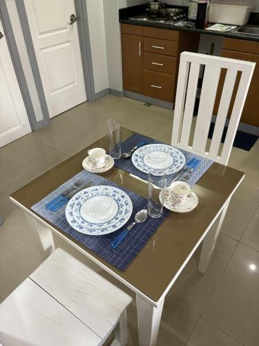 a table with two chairs and plates and drinks on it at Studio condo near SM Clark, clark, & clark airport in Malabañas