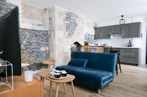 un salon avec un canapé bleu et une cuisine dans l'établissement Appartement charme de l'ancien - Centre ville Angers- 2 personnes, à Angers