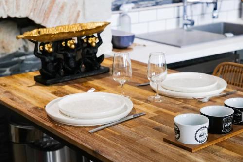 - une table avec 2 assiettes blanches et des verres à vin dans l'établissement Appartement charme de l'ancien - Centre ville Angers- 2 personnes, à Angers