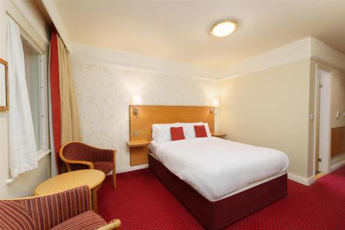 a hotel room with a bed and two chairs at Best Western Plus Milford Hotel in South Milford