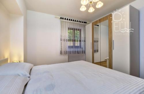 a bedroom with a large white bed and a mirror at Centar in Mali Lošinj