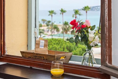 a glass of orange juice and flowers on a window sill at Bastion Ideally located, brightness, sea views in Menton