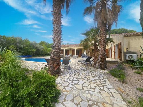 une maison avec des palmiers et une piscine dans l'établissement La Cerisette, à Félines-Minervois