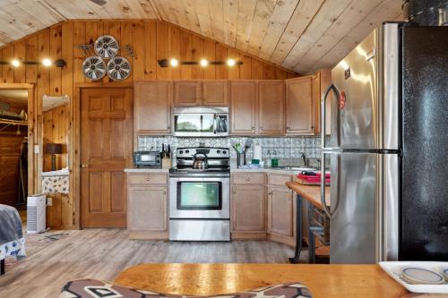 a kitchen with wooden cabinets and a stainless steel refrigerator at Basin Perch Basin Views Sunsets AC Deck in Plum Island