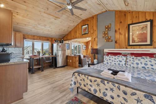 a bedroom in a cabin with a bed and a kitchen at Basin Perch Basin Views Sunsets AC Deck in Plum Island