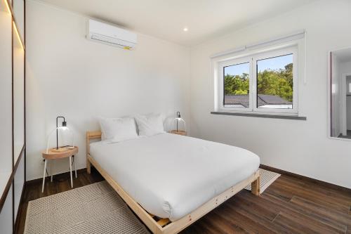 a white bedroom with a large bed and a window at WHome Modern House With Balcony & AC Close To The Sea in Alcabideche