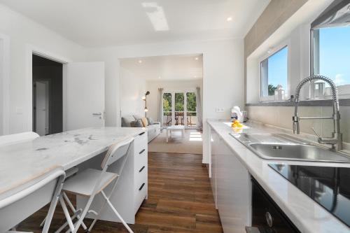 a kitchen with white counters and a large counter top at WHome Modern House With Balcony & AC Close To The Sea in Alcabideche