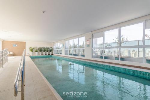 a large swimming pool in a building with windows at Studios Modernos no Setor Bueno WBU in Goiânia