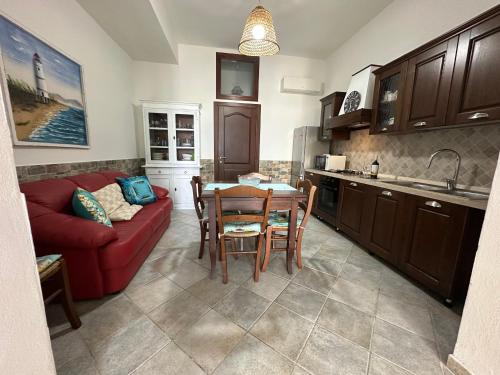 a kitchen and living room with a red couch and a table at Casa di Flavio in Castelsardo