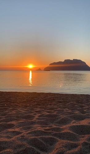 a sunset on a beach with the sun setting over the water at Orchidea in Olbia