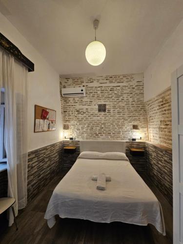 een slaapkamer met een bed en een bakstenen muur bij Recuerdos de la Abuela in Sevilla
