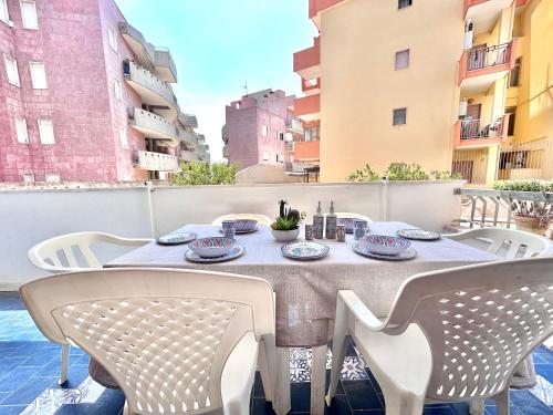 a table on a balcony with chairs and plates on it at Quadrilocale vista mare completamente climatizzato in Gallipoli