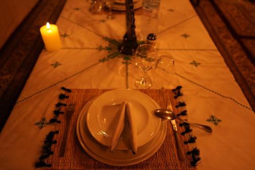 a table with a white plate and a candle and a candle at Arabian Nights Desert Camp Merzouga in Lac Yasmins