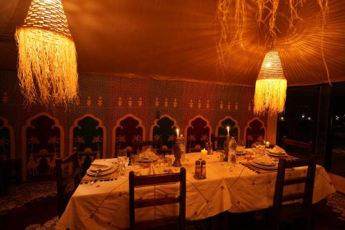 a dining table with a white table cloth and chandeliers at Arabian Nights Desert Camp Merzouga in Lac Yasmins