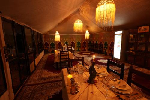 a dining room with a table with candles in it at Arabian Nights Desert Camp Merzouga in Lac Yasmins