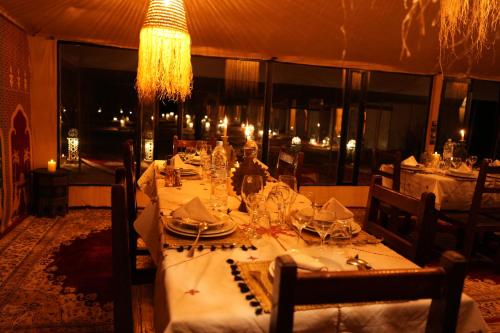 a table in a restaurant with a white table cloth at Arabian Nights Desert Camp Merzouga in Lac Yasmins