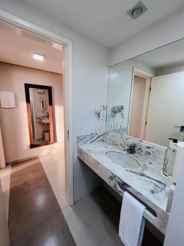 a bathroom with a sink and a large mirror at Atibaia Residence Hotel & Resort in Atibaia
