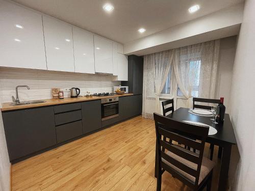 a kitchen with a table and chairs and a kitchen with white cabinets at Testimitanu Star Kids in Chişinău