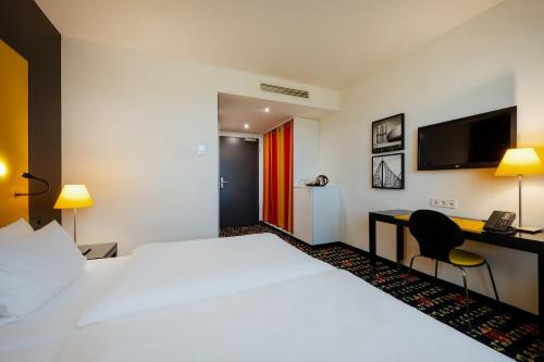 a hotel room with a large bed and a desk at Holiday Inn Munich - Westpark by IHG in Munich